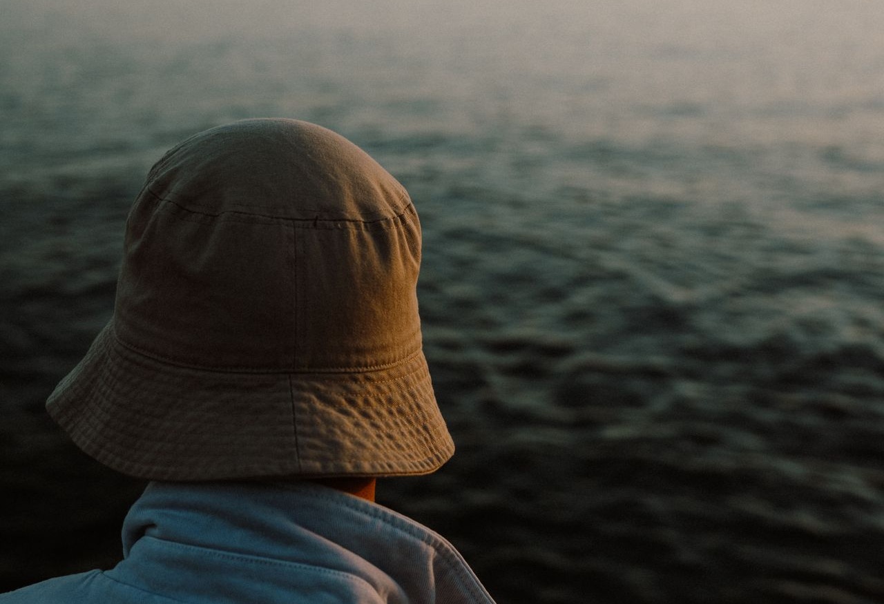 Person wearing bucket hat while looking at ocean