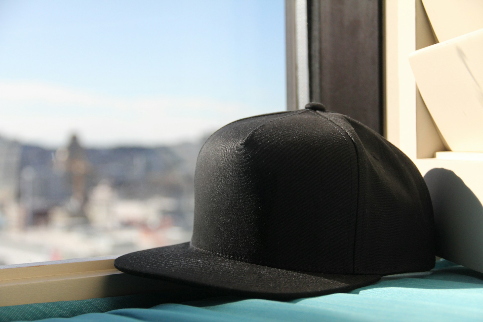 Black fitted baseball cap next to window