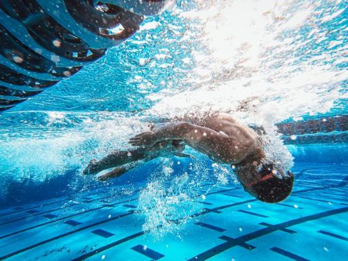 Person swimming underwater in pool